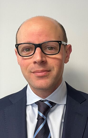 A man in a suit and glasses, exuding professionalism and confidence.